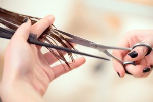 Getting rid of those split ends. Cropped shot of a female hairdresser cutting clients hair with scissors at beauty salon